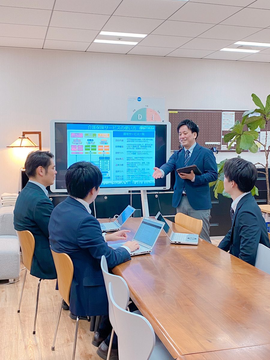 モニターを使って説明する社員と、話を聞くメンバー