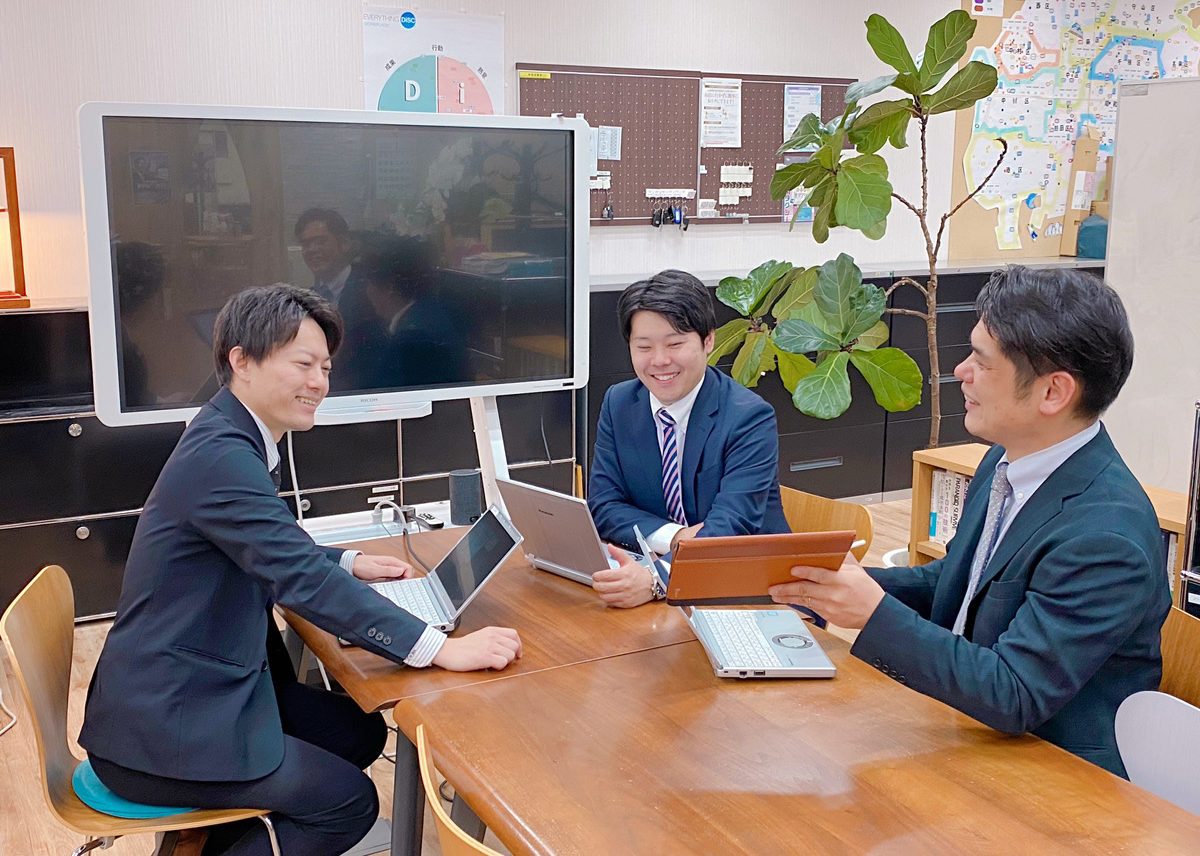 テーブルを囲んで打ち合わせをする3人の社員